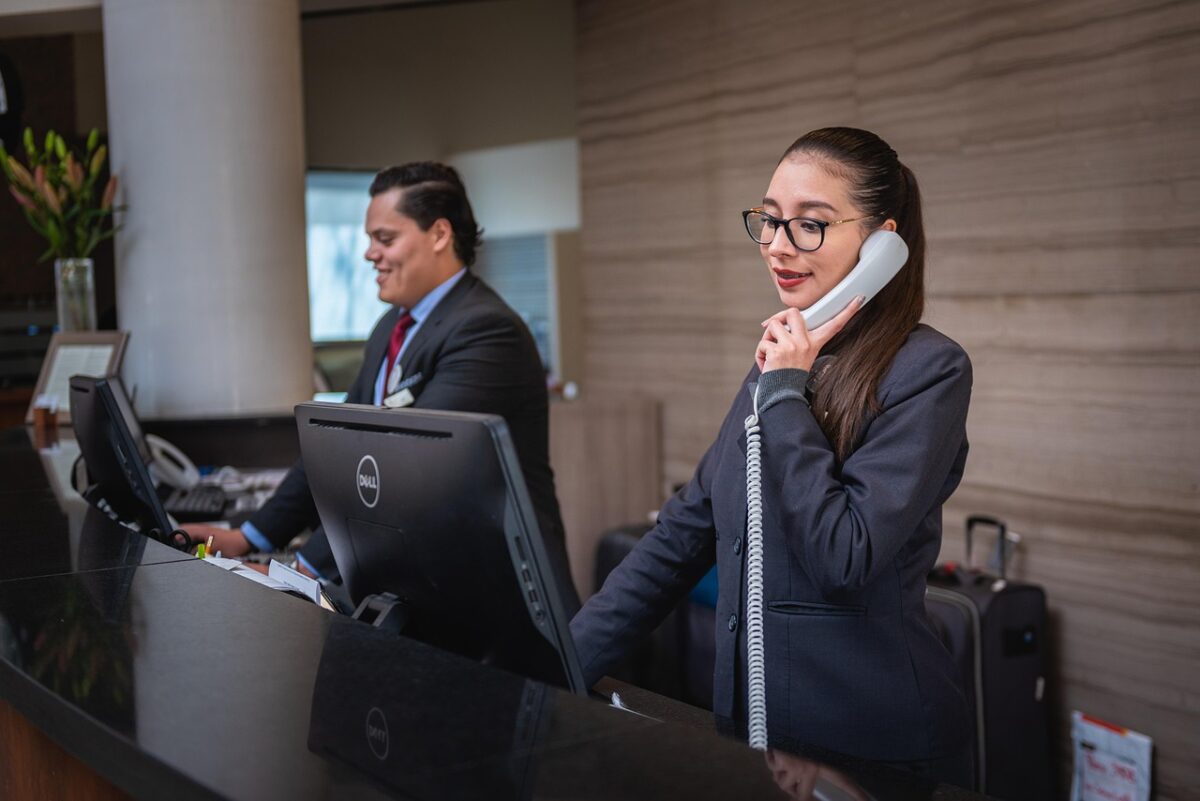 A staff member is answering the phone at the front desk of the hotel